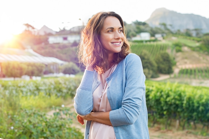 A woman standing in a field of wine grapes.