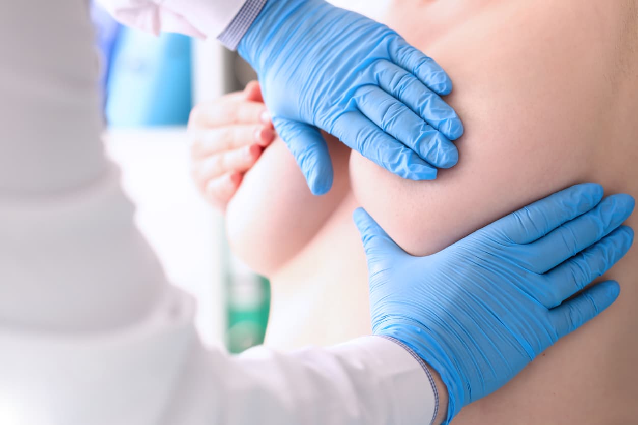 close up of torso of topless woman while doctors with gloves are working on her