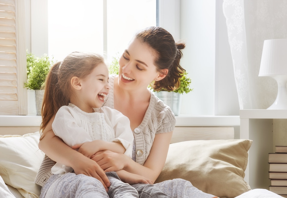 A mother with a young girl in her arms laughs and smiles