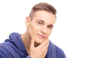 Studio shot of a young man checking the skin on his face